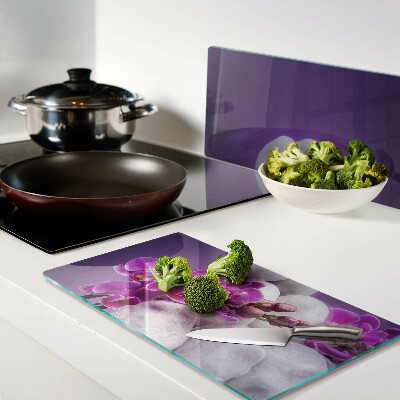 Glass chopping board Orchid flowers on a background of stones