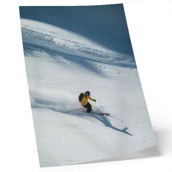 Poster skier in a yellow jacket on a snowy slope with a shadow