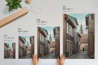 Poster narrow street with tenement houses, a tower, and a figure in a blue coat