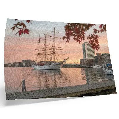 Decorative canvas print Sailing ship at sunset with a peaceful cityscape panorama